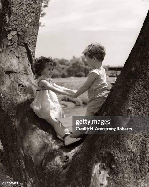 boy girl holding hands look one another standing y tree trunk friend friendship romance romantic friends boys girls child children couple. - 1930 stock pictures, royalty-free photos & images