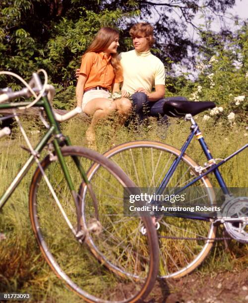 young adults teenagers field date bikes bicycles flowers (1970 1970s retro). - young love stock-fotos und bilder