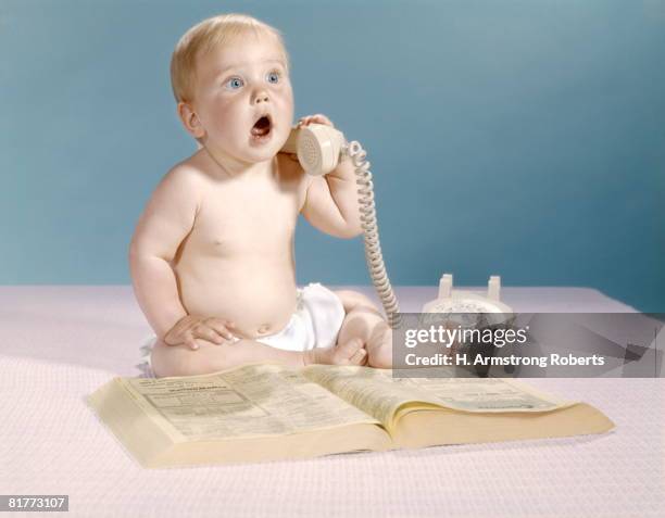 baby with telephone directory holding telephone receiver and talking studio. - telephone directory stock pictures, royalty-free photos & images