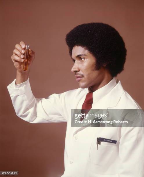 african-american man doctor chemist pharmacist scientist holding up test tube science research diagnostic. - 1970 stock pictures, royalty-free photos & images