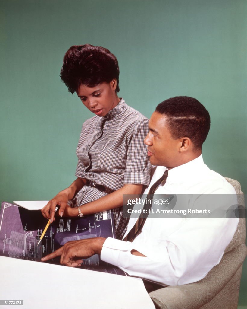 African-American Couple Man Woman Going Over Blueprints.