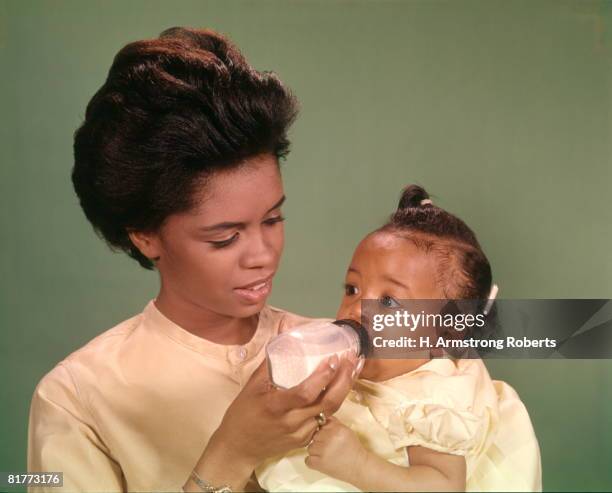 african-american woman mother feeding baby with bottle babies women mothers family families parenting. - 1960s baby stockfoto's en -beelden