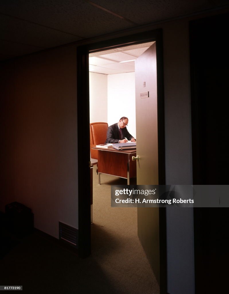 Lone Man Woking In Office Door Ajar Partly Open.
