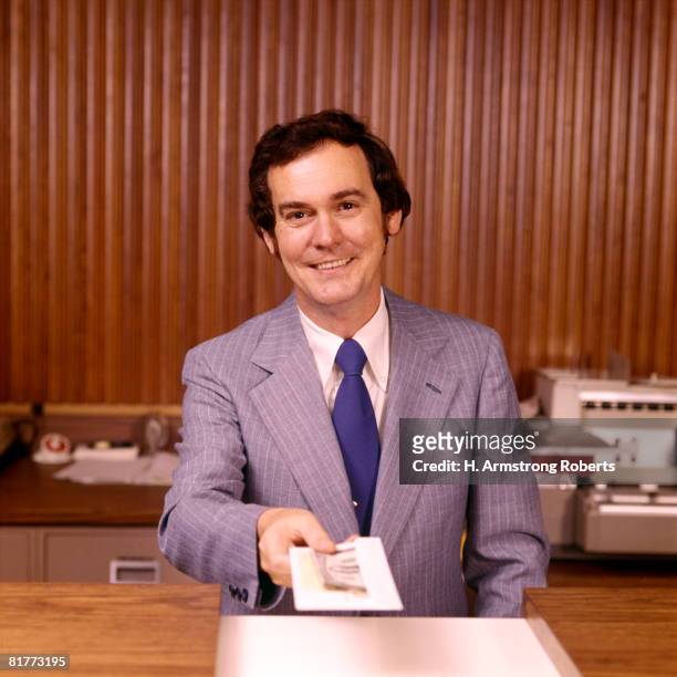 smiling man bank teller handing money receipt over counter banks tellers financial customer service. - 1970 stock pictures, royalty-free photos & images