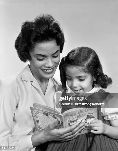 afro-american mother & daughter looking down reading book together. - lee armstrong fotografías e imágenes de stock