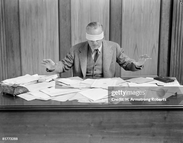 blindfolded businessman at desk covered with papers. - paperweight stock pictures, royalty-free photos & images