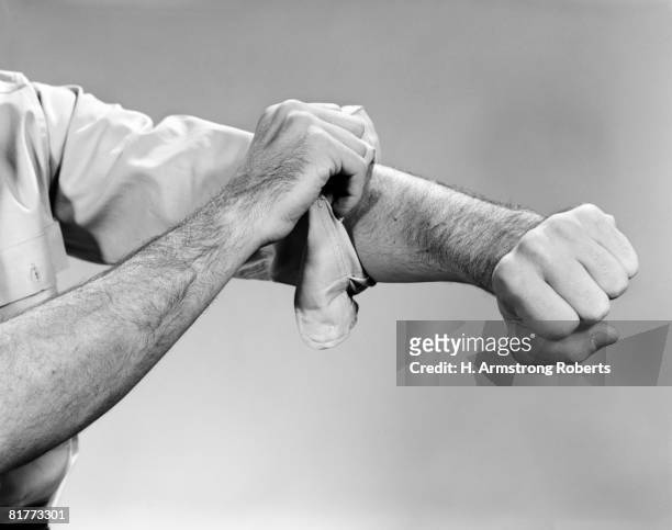 bare arm & hand rolling up the sleeve of the clenched fist right arm hairy worker robust. - sleeve roll stock pictures, royalty-free photos & images