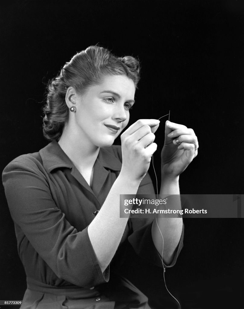 Woman In A Dark Dress Threading A Needle With Her Hands Stark Serious Dramatic.