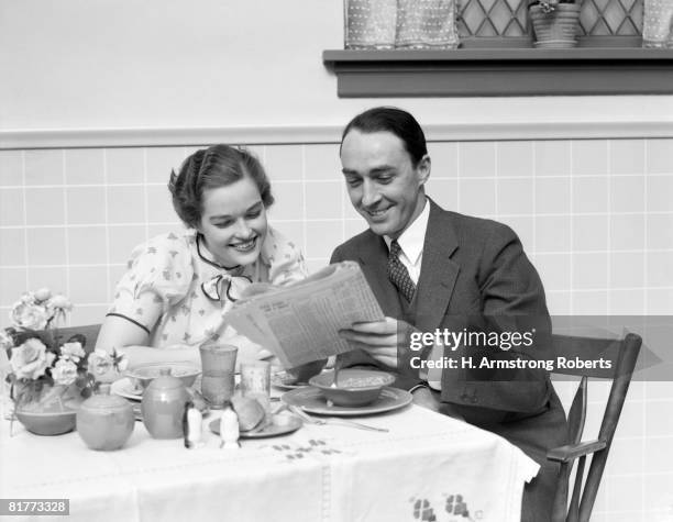 man woman couple at breakfast table reading newspaper together smiling. - media breakfast stock pictures, royalty-free photos & images