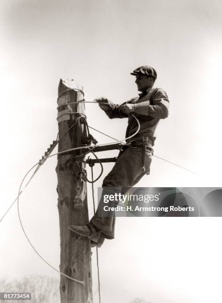 man worker, working atop utility pole, installing electric wires for power utilities. - telephone pole stock pictures, royalty-free photos & images
