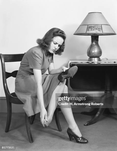 woman sitting in chair, rubbing her feet. (photo by h. armstrong roberts/retrofile/getty images) - lamp shade fotografías e imágenes de stock