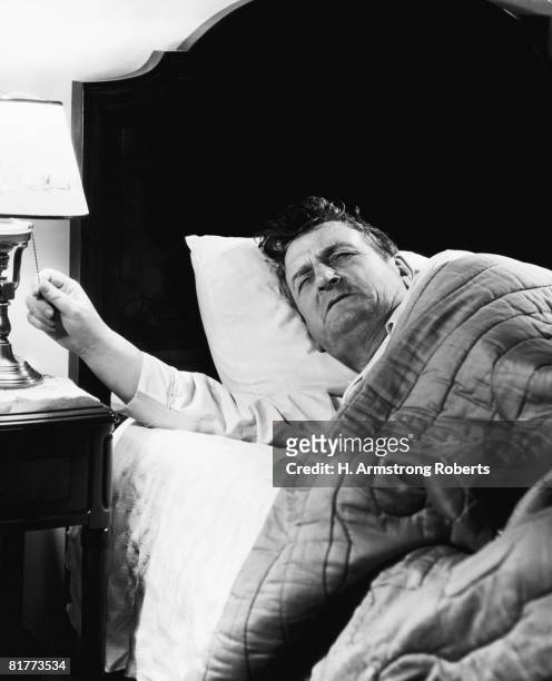 man waking up, turning on light, 6.30am on alarm clock. - 1940 stock pictures, royalty-free photos & images
