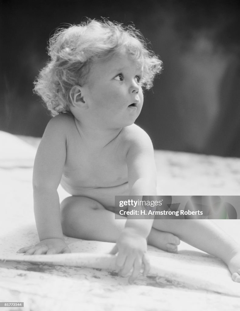 Baby sitting on bed. (Photo by H. Armstrong Roberts/Retrofile/Getty Images)