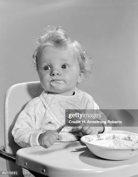 baby sitting in highchair, face smeared with food. - funny baby photo - fotografias e filmes do acervo