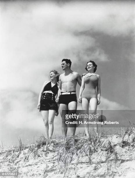 man and two women standing on beach sand dune. - année 30 photos et images de collection