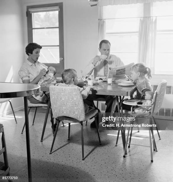 family of five eating breakfast at kitchen table. - 1950s father stock-fotos und bilder