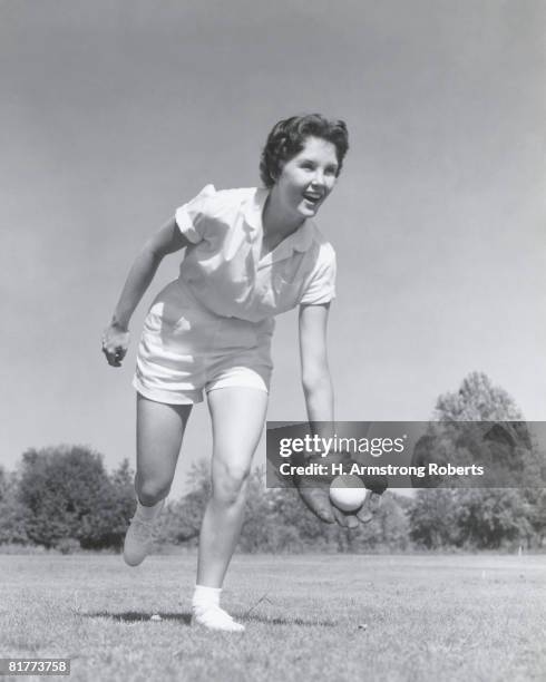 young woman catching baseball in glove. (photo by h. armstrong roberts/retrofile/getty images) - softball sport stock-fotos und bilder