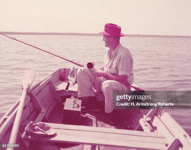 man sitting in rowing boat, fishing. (photo by h. armstrong roberts/retrofile/getty images) - headware stock pictures, royalty-free photos & images