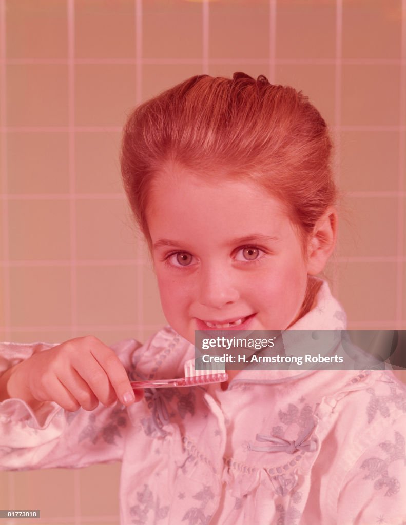 Girl, wearing bathrobe, brushing her teeth in bathroom. (Photo by H. Armstrong Roberts/Retrofile/Getty Images)