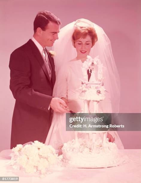 bride and groom cutting the wedding cake. (photo by h. armstrong roberts/retrofile/getty images) - vintage wedding stock pictures, royalty-free photos & images