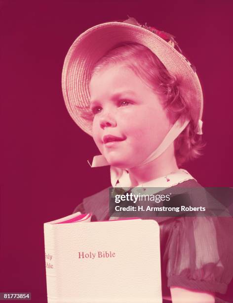 girl wearing straw hat, holding bible. (photo by h. armstrong roberts/retrofile/getty images) - headware stock pictures, royalty-free photos & images