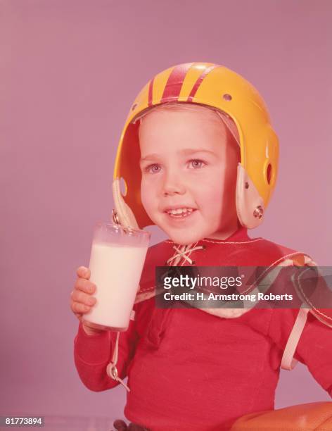 boy wearing american football kit, holding glass of milk. (photo by h. armstrong roberts/retrofile/getty images) - football uniform stock pictures, royalty-free photos & images