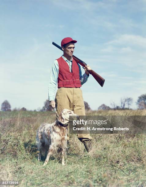 male hunter infield with dog, gun resting on shoulder. (photo by h. armstrong roberts/retrofile/getty images) - headware stock pictures, royalty-free photos & images