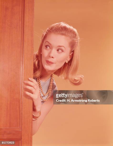young woman playfully peeking around door. (photo by h. armstrong roberts/retrofile/getty images) - peer imagens e fotografias de stock