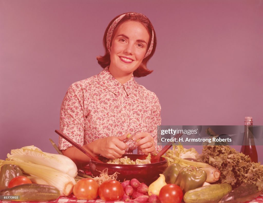 Woman by kitchen counter, tossing vegetables for salad. (Photo by H. Armstrong Roberts/Retrofile/Getty Images)