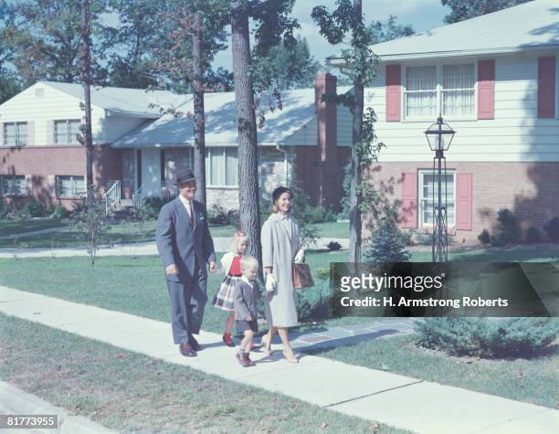 family with two children walking along suburban street. (photo by h. armstrong roberts/retrofile/getty images) - suburban family stock pictures, royalty-free photos & images