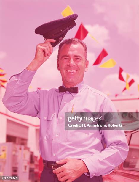 service station attendant smiling and lifting hat in greeting gesture. (photo by h. armstrong roberts/retrofile/getty images) - gas station attendant stock pictures, royalty-free photos & images