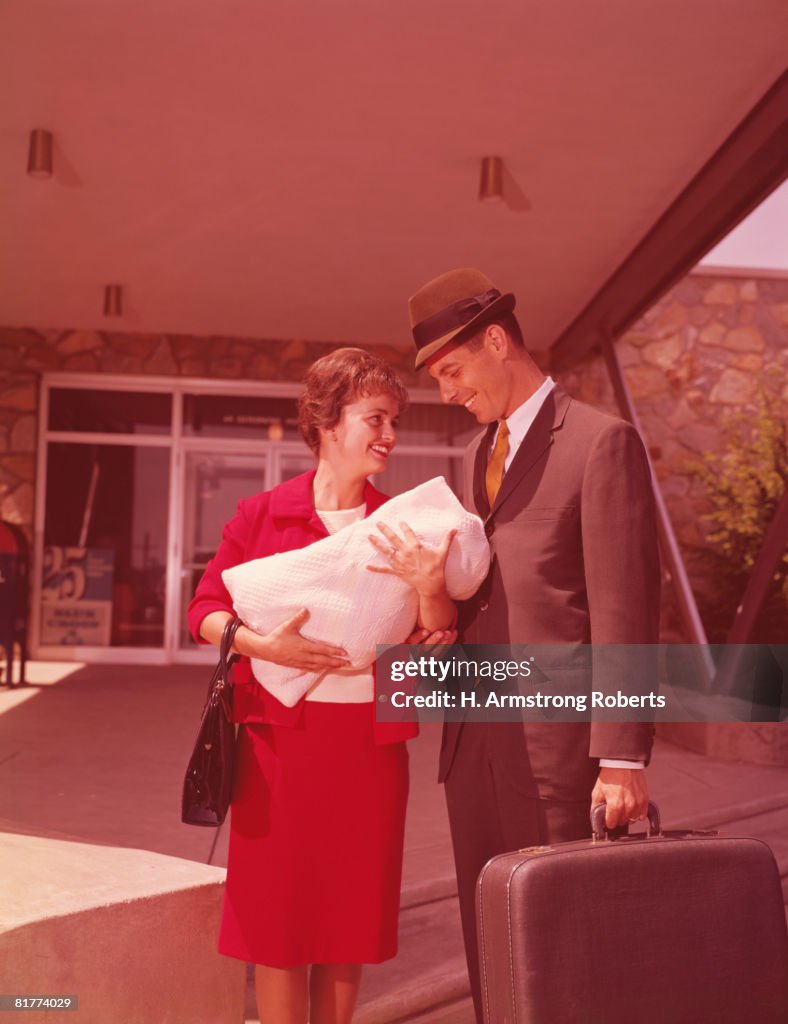 Mother and father leaving hospital with newborn baby.