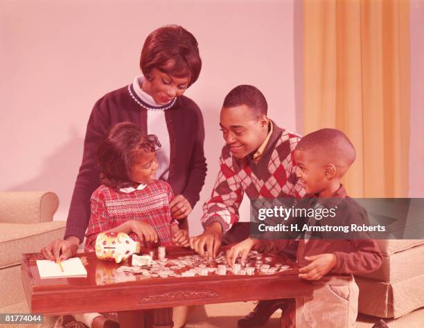 family saving money in piggy bank. - swinging sixties stock pictures, royalty-free photos & images