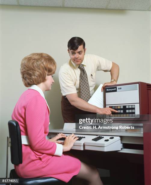 man helping woman with data entry computer. (photo by h. armstrong roberts/retrofile/getty images) - vintage computer stock pictures, royalty-free photos & images