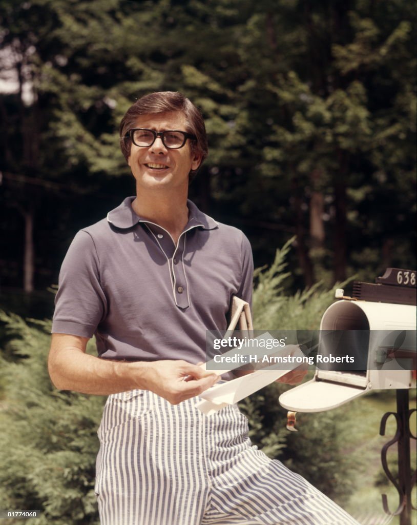 Man taking mail from rural mail box.