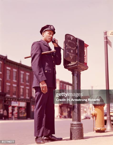 police officer using telephone at street police callbox. (photo by h. armstrong roberts/retrofile/getty images) - emergency telephone box stock pictures, royalty-free photos & images