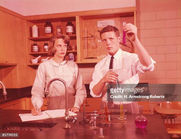 two students in chemistry laboratory, conducting experiment, boy holding test-tube, girl making notes. - 1960 個照片及圖片檔