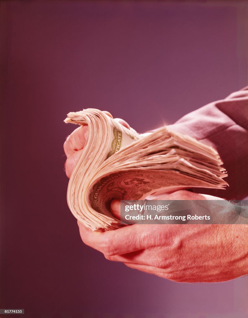 Hands flipping through currency. (Photo by H. Armstrong Roberts/Retrofile/Getty Images)