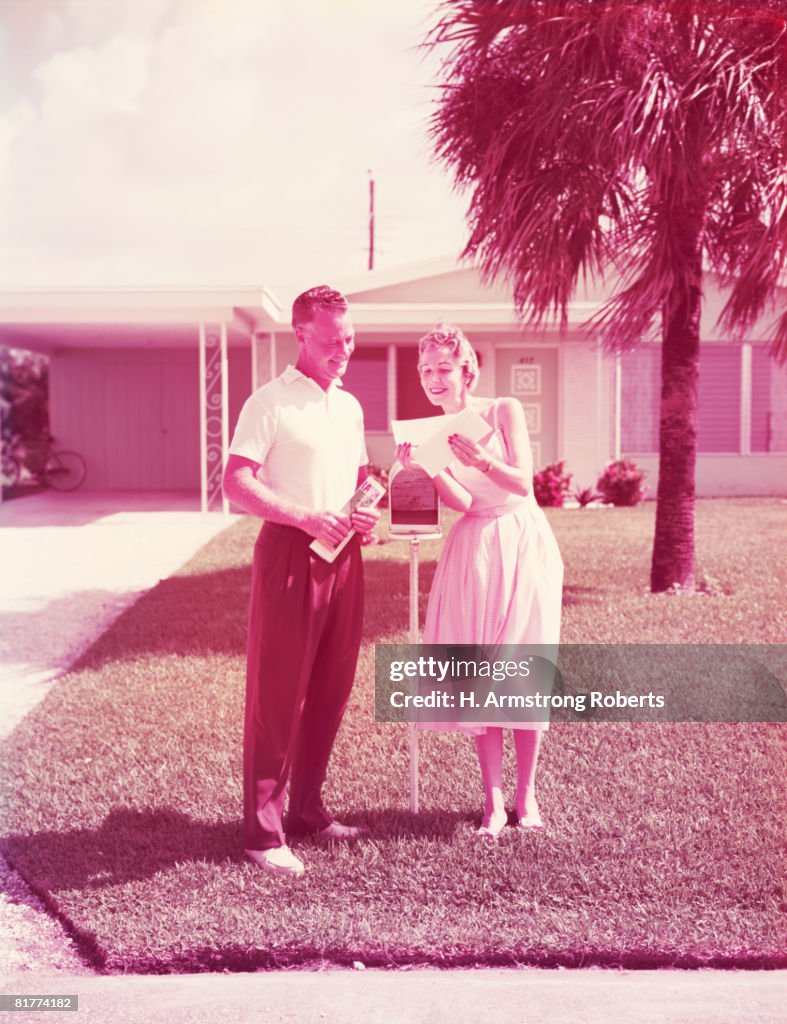 Couple retrieving mail at front yard mailbox. (Photo by H. Armstrong Roberts/Retrofile/Getty Images)