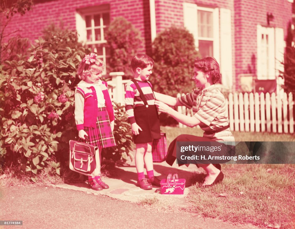 Mother preparing daughter and son to go to school with lunch boxes, books and bags. (Photo by H. Armstrong Roberts/Retrofile/Getty Images)