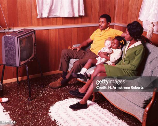 parents and young daughter sitting in living room, watching television. (photo by h. armstrong roberts/retrofile/getty images) - african american watching tv stock pictures, royalty-free photos & images