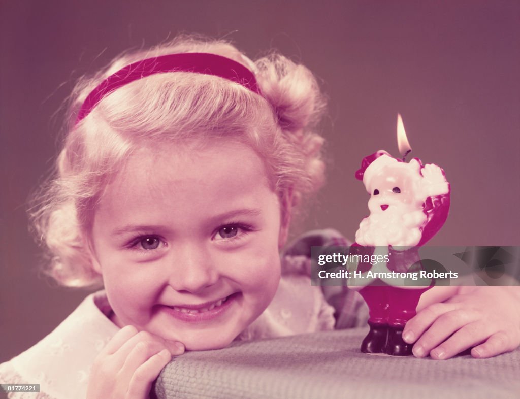 Girl holing Father Christmas candle, smiling, portrait. (Photo by H. Armstrong Roberts/Retrofile/Getty Images)