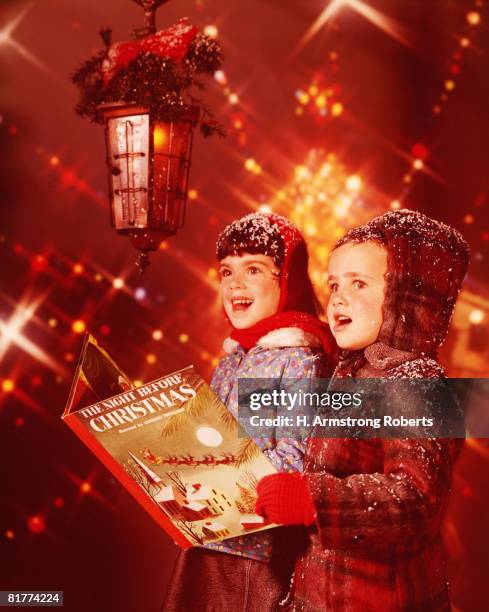 two children singing christmas carols. - christmas carols foto e immagini stock