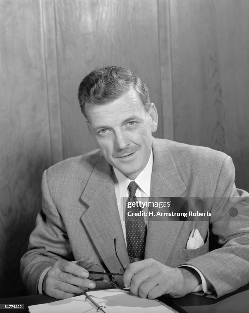 Portrait of a business man, seated at a desk.