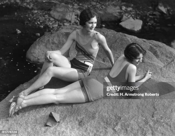 two women relaxing on rock, by creek. (photo by h. armstrong roberts/retrofile/getty images) - 1920 - fotografias e filmes do acervo