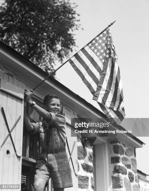 young boy raising american flag in front of house. (photo by h. armstrong roberts/retrofile/getty images) - retrofile foto e immagini stock