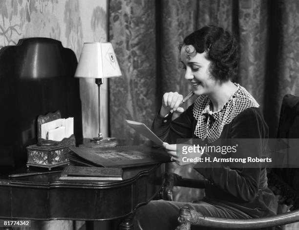 woman sitting at desk at home, writing a letter. (photo by h. armstrong roberts/retrofile/getty images) - retrofile foto e immagini stock