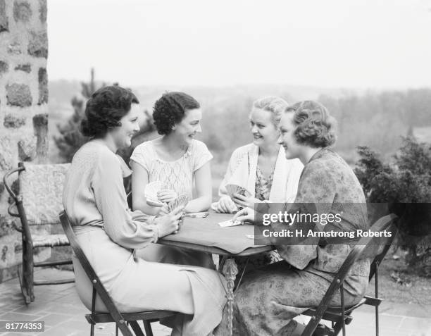 four women seated at table on porch of house, playing cards. (photo by h. armstrong roberts/retrofile/getty images) - retrofile foto e immagini stock