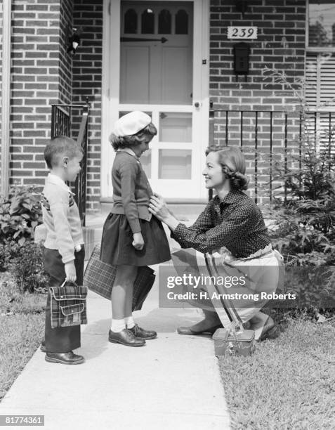 mother outside front door, buttoning sweater of daughter going off to school with her brother. (photo by h. armstrong roberts/retrofile/getty images) - retrofile foto e immagini stock