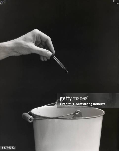 man's hand squeezing eyedropper over bucket. (photo by h. armstrong roberts/retrofile/getty images) - retrofile foto e immagini stock